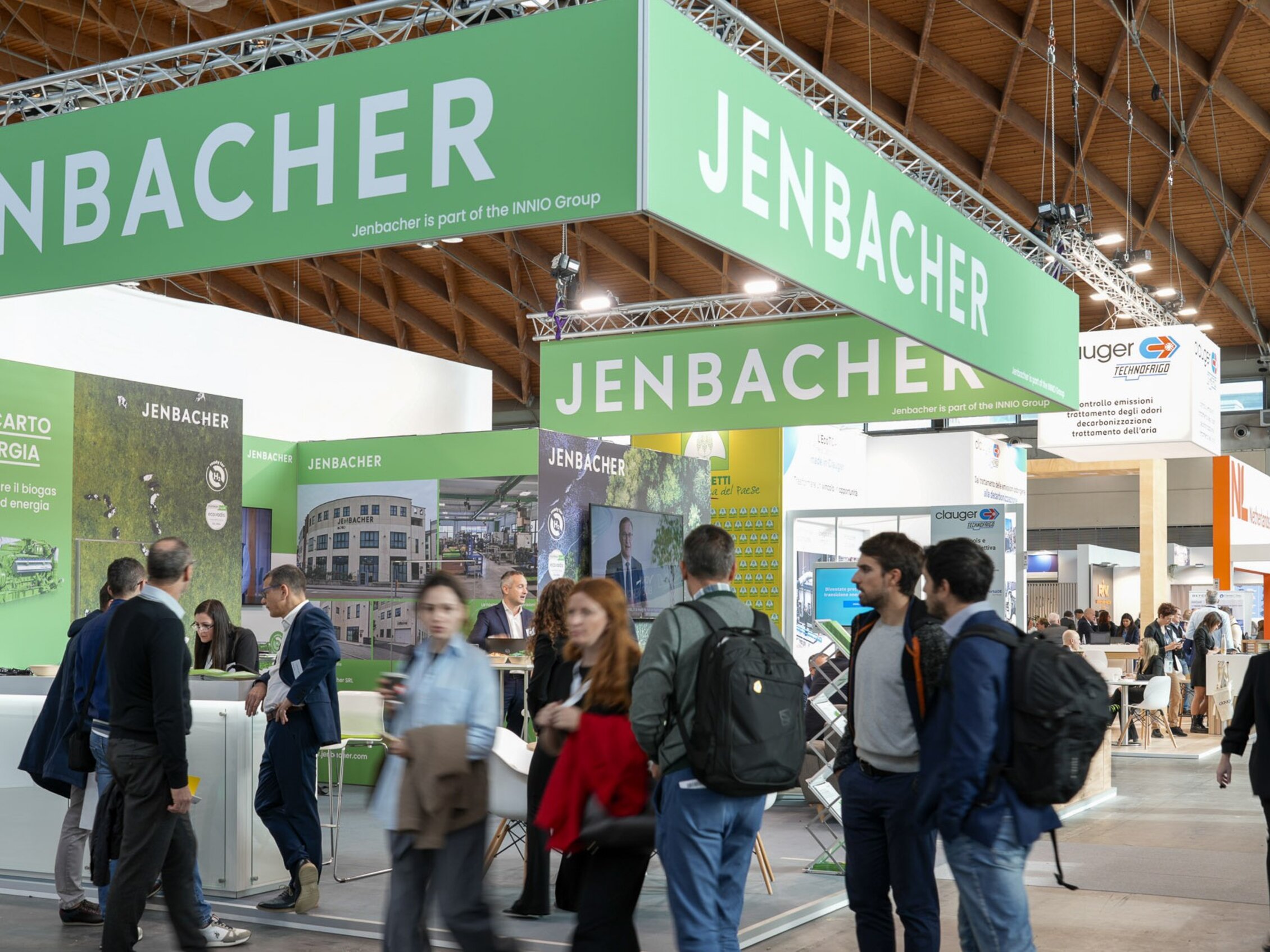 Visitatori passano accanto allo stand di Jenbacher, nel loro pannello grafico spicca lo slogan 'Da scarto a energia'