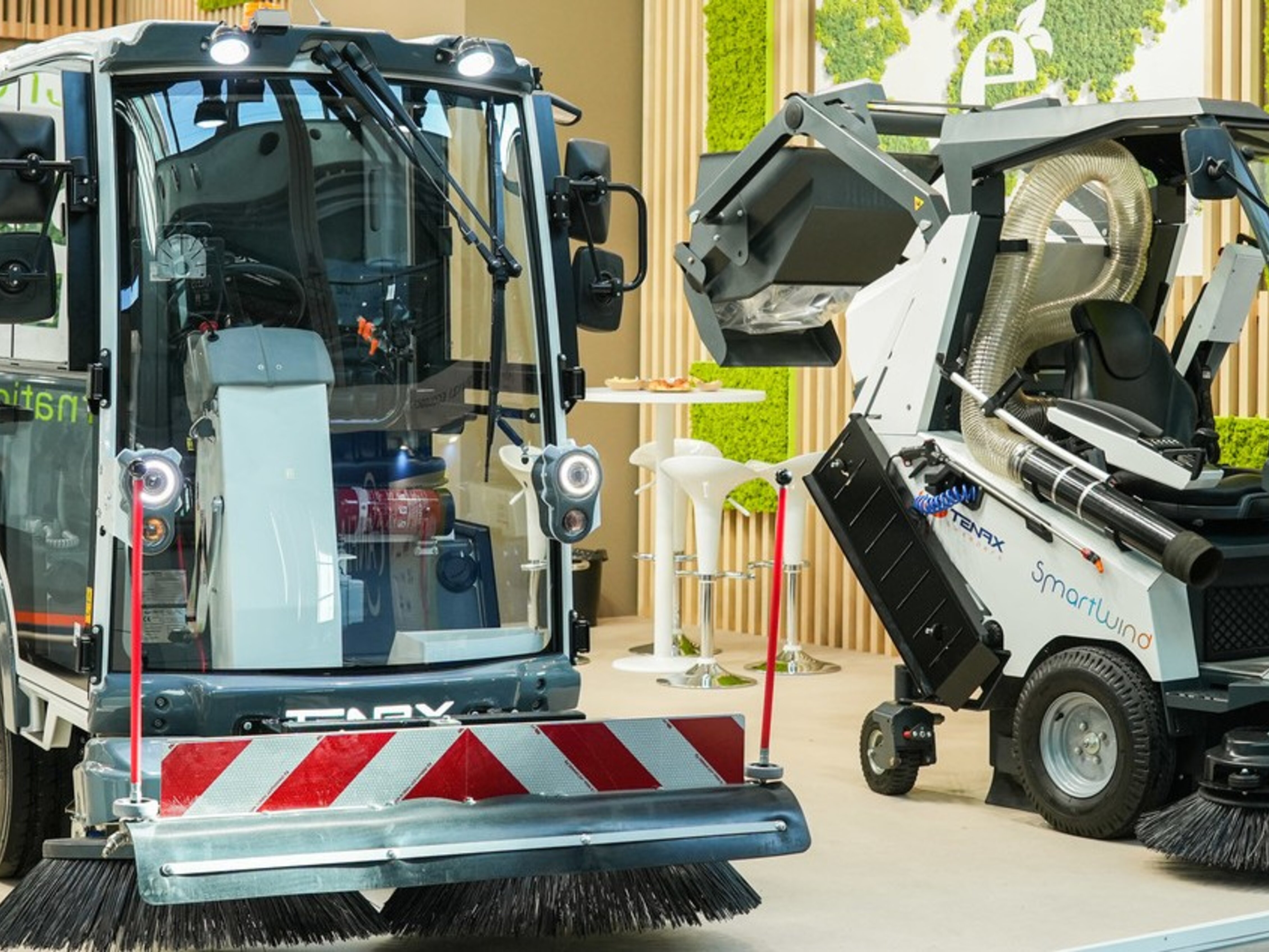 Due spazzatrici stradali elettriche esposte in uno stand di Ecomondo con pareti verdi verticali