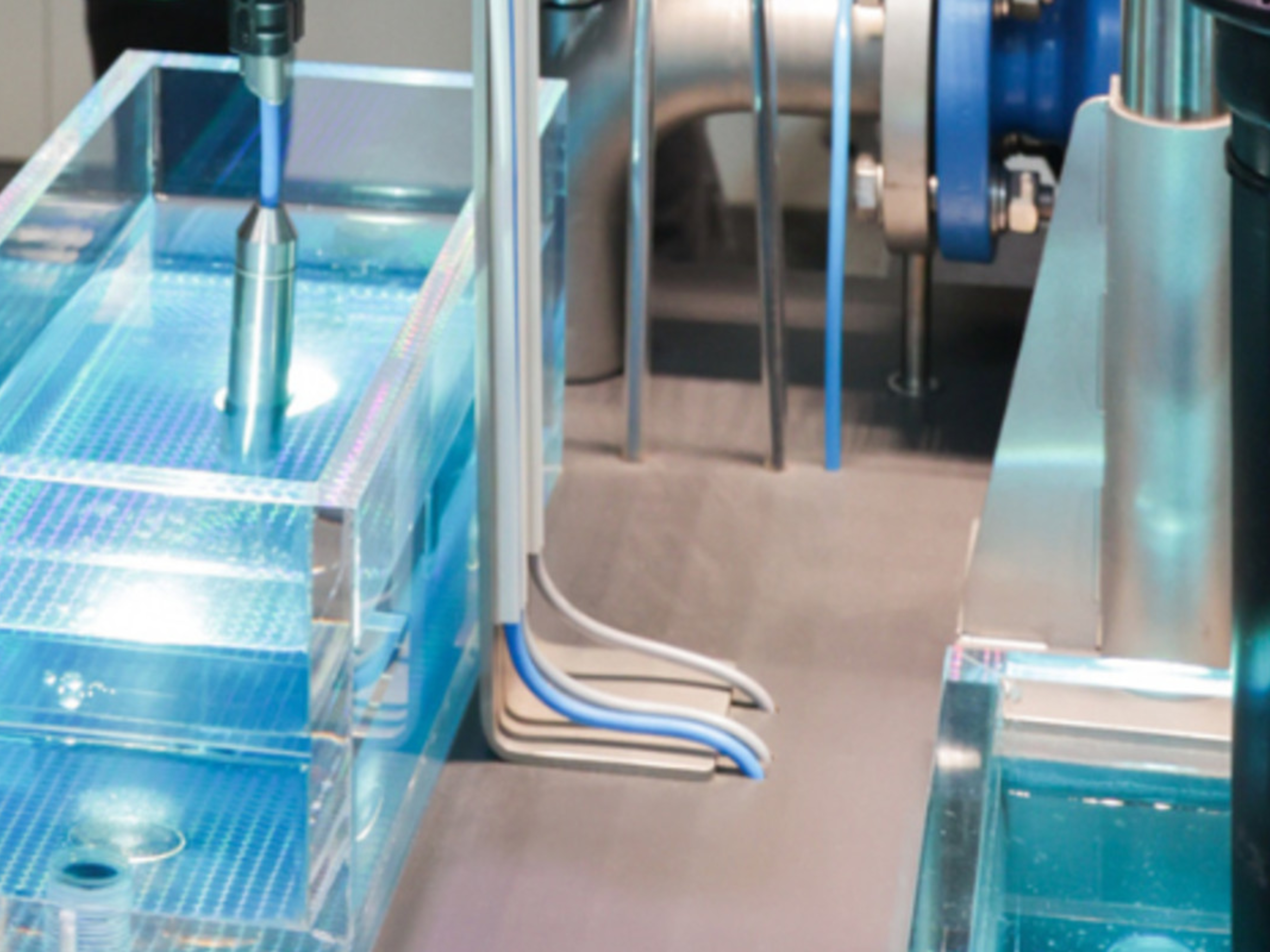 Machine containing water inside transparent tanks, with several tubes, sensors, and metal fittings connected
