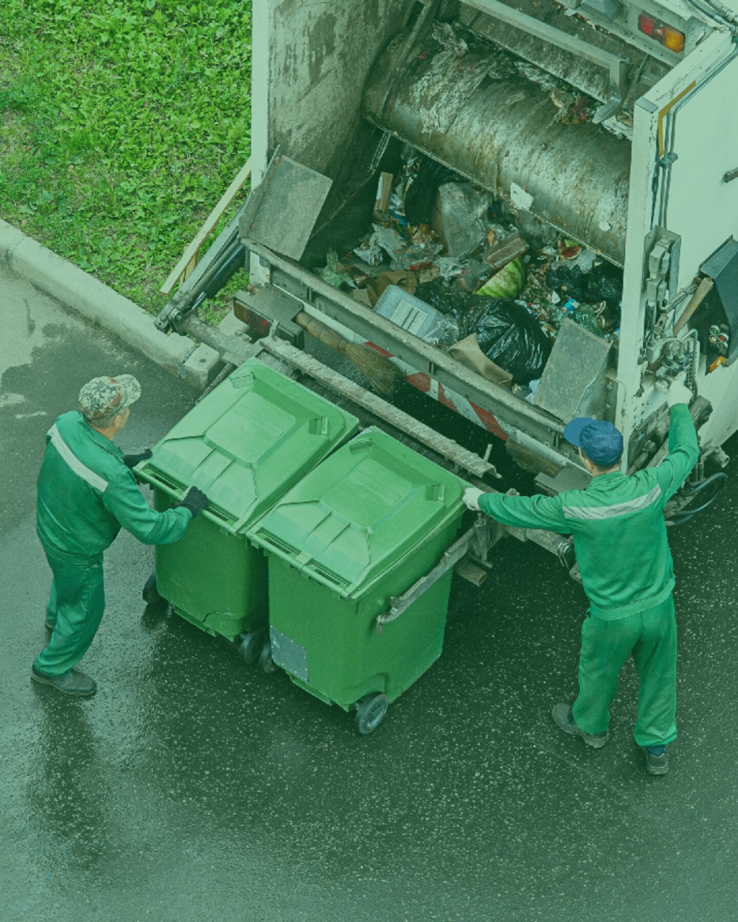 Due operatori ecologici in uniforme caricano bidoni della spazzatura su un camion compattatore Due operatori ecologici in uniforme caricano bidoni della spazzatura su un camion compattatore